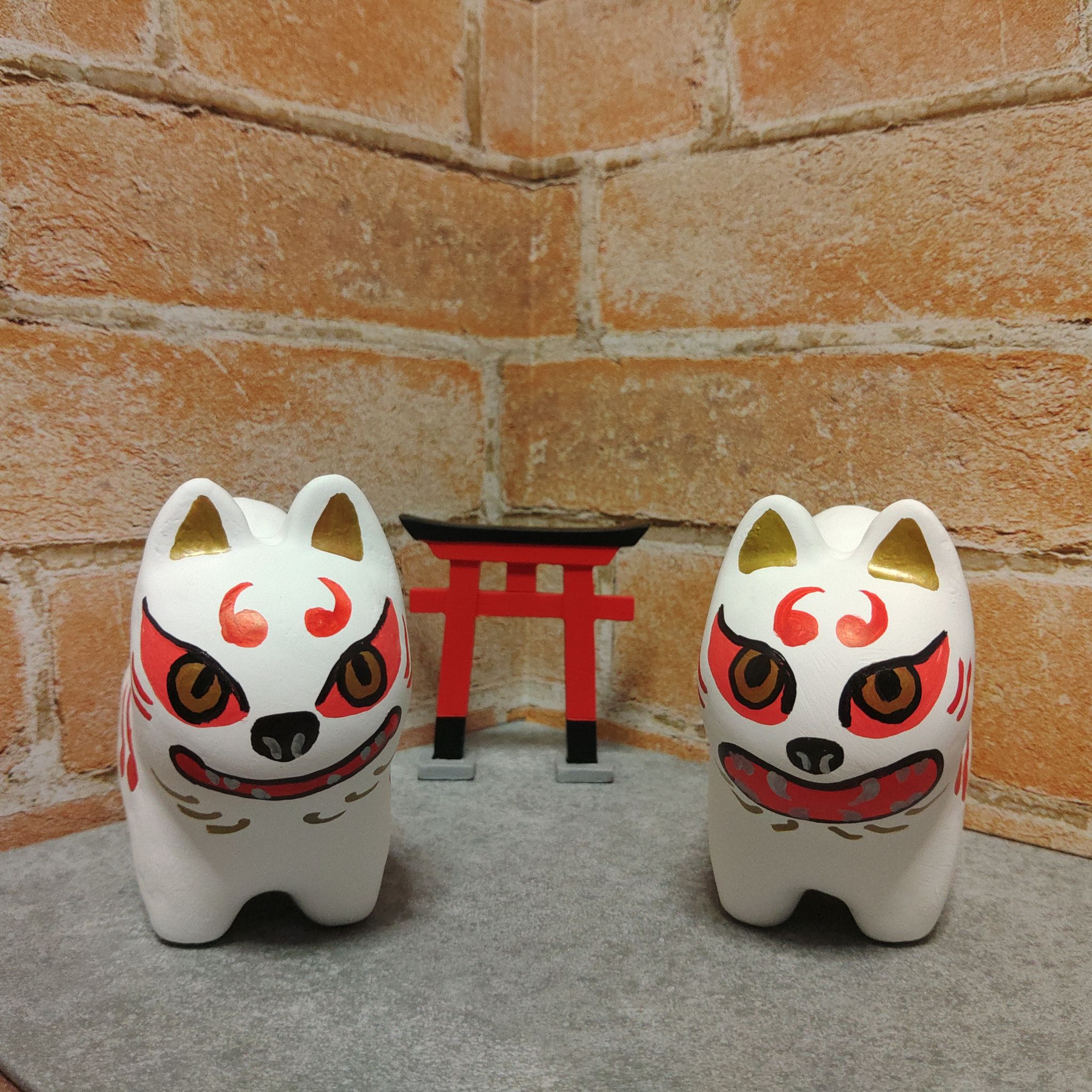 琥珀ぬこの作品「狛犬」。白い狛犬の置物が二体、赤い鳥居の前に並んでいる。